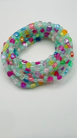 Colorful multicolor glass bead African waist beads in mint, pink, and rainbow tones, coiled on a neutral background