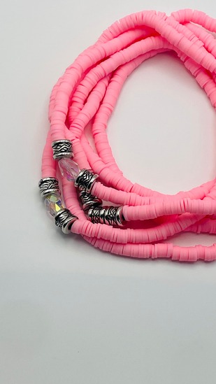 Bubblegum pink clay disc African waist beads with silver spacer beads, coiled on a neutral background