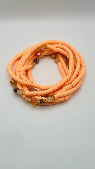 Peach coral African waist beads, coiled on a neutral background