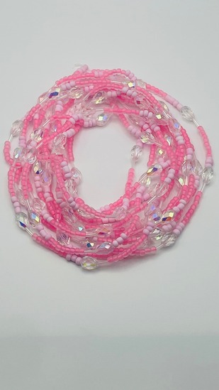 Cotton candy pink and white mixed bead African waist beads with crystal accents, coiled on a neutral background