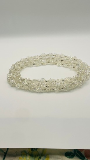 Crystal white pearl African waist beads, coiled on a neutral background