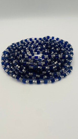 Navy blue cube African waist beads with silver spacer beads, coiled on a neutral background