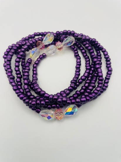 Purple African waist beads with iridescent crystal accent beads, coiled on a neutral background