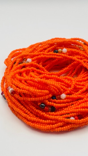 Sunset orange seed bead African waist beads with multicolor accent beads, coiled on a neutral background