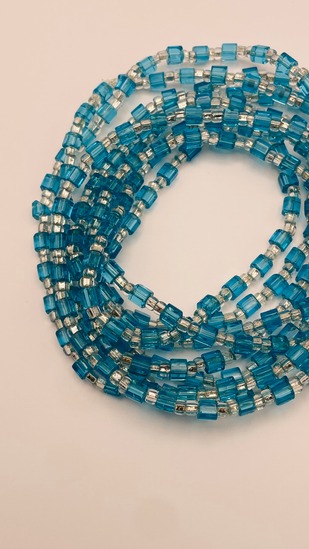 Teal glass cube African waist beads, coiled on a neutral background